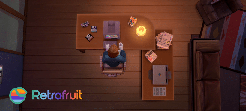 Retrofruit: Technology Of The Past Meets The Sims 4 15 A top-down view of a sim sitting at an L-shaped desk. He works on the iPlum Classic computer with floppy discs and USBs to his left. On the right the second arm of the desk holds a a printer and several stacks of documents.